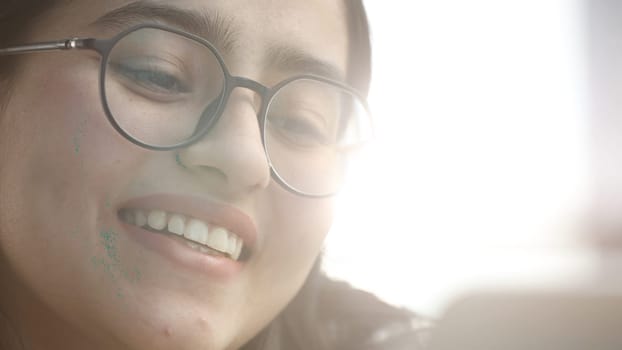 A young woman with glasses in the office is working with a laptop.