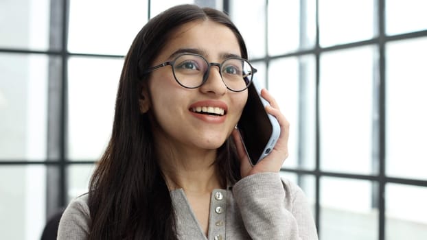 The face of a young successful woman in close-up with glasses in the office.