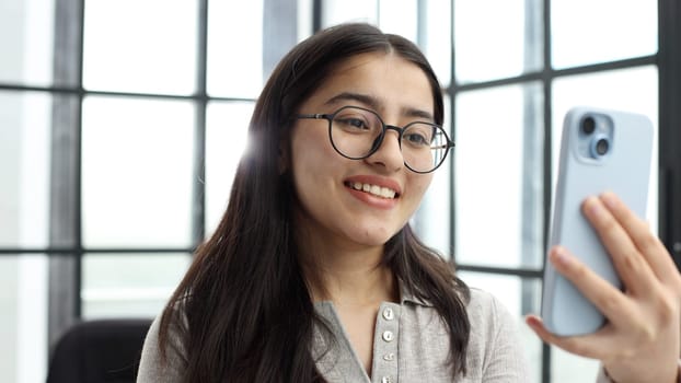 The face of a young successful woman in close-up with glasses in the office.