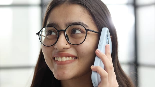 The face of a young successful woman in close-up with glasses in the office.