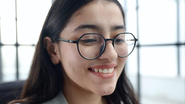 The face of a young woman in close-up with glasses.