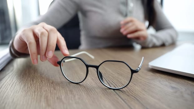 A young woman takes glasses from a table close-up in the office.