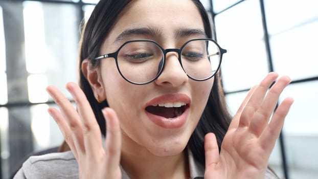 A young woman's face in close-up with glasses in the office, she is surprised.