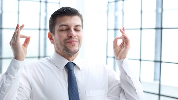 Male office worker close-up in office meditating.