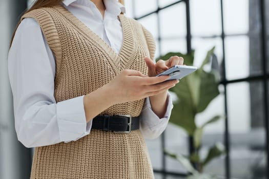 Cheerful student woman sitting at table break holding mobile phone surfing internet