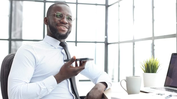 A businessman man in a shirt is talking on the phone in the office in close-up.