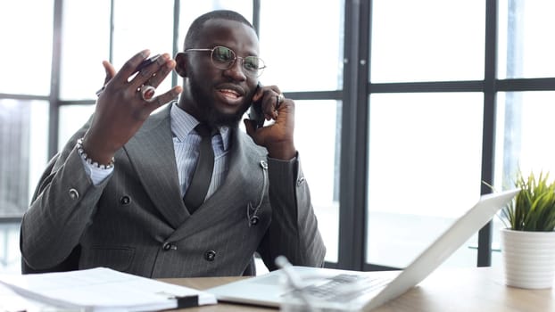 A businessman man in a close-up in a jacket, he is talking on the phone in the office.