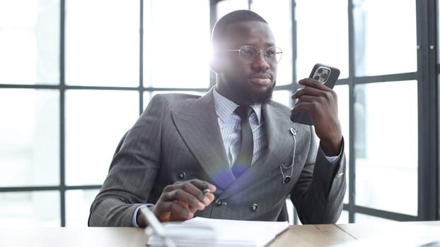 A businessman man in a close-up in a jacket, he is talking on the phone in the office.