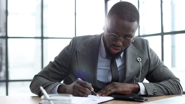 A businessman man in a close-up in a jacket, he writes and checks documents in the office.
