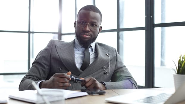 A businessman man in a close-up in a jacket looks at the camera in the office.