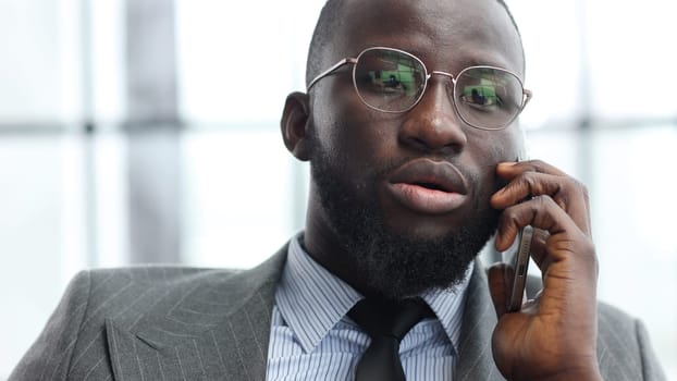 The face of a businessman man in a close-up in a jacket in the office talking on the phone.