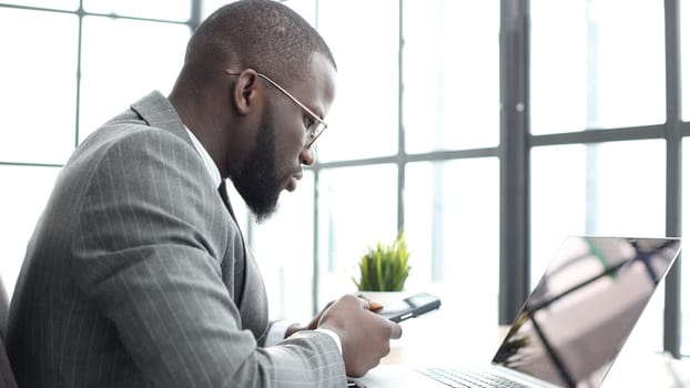 A businessman man in a close-up in a jacket in the office talking on the phone.