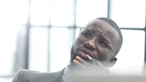 The face of a businessman man in a close-up in a jacket in the office, he is working with a laptop.