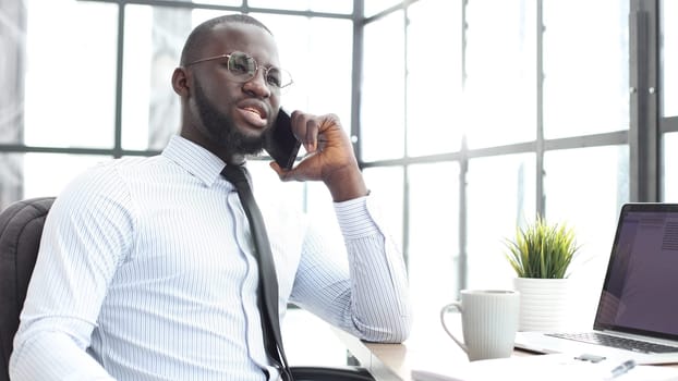 A businessman man in close-up in a shirt in the office talking on the phone.