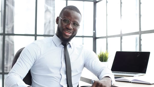 A businessman man in close-up in a shirt in the office looks at the camera.