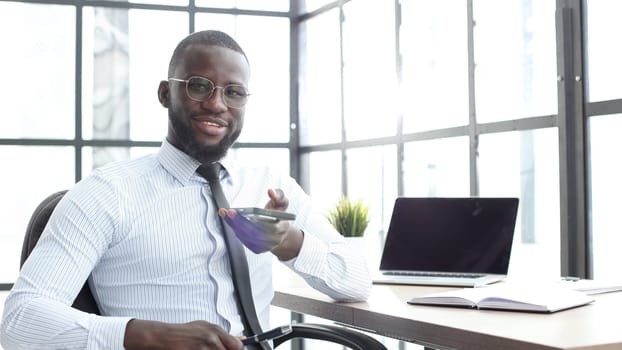 A businessman man in close-up in a shirt in the office talking on the phone.