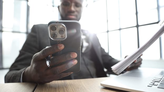 A businessman man in a close-up in a jacket in the office, he uses a phone.