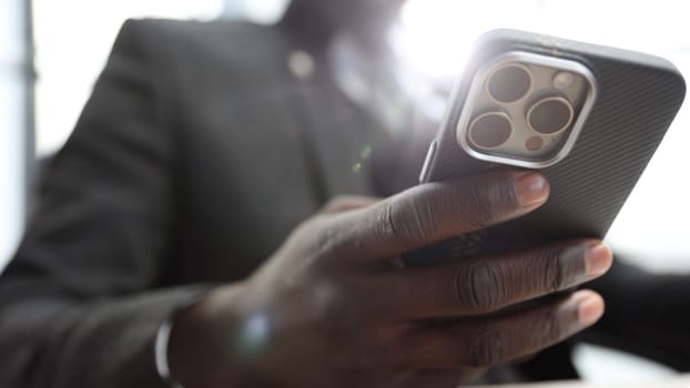 A businessman man in a close-up in a jacket in the office, he uses a phone.