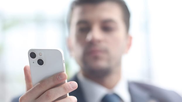 A male businessman uses a phone in close-up.