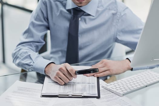 man looking through a magnifying glass to documents notebook.