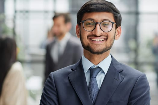 Handsome young business man in glasses standing confidently in the office