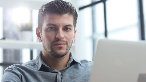 The man's face is in close-up, he is using a laptop.