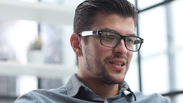 The man's face is in close-up with glasses, he looks thoughtfully away.