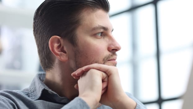 The man's face is in close-up with glasses, he looks thoughtfully away.