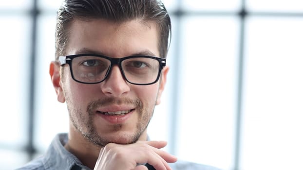 A man's face in close-up with glasses looks at the camera.
