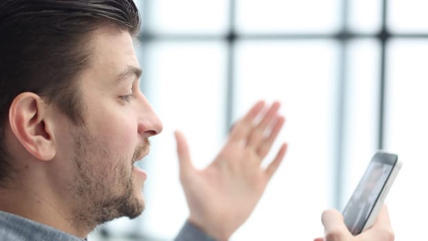 A man's face is in close-up, he is using a phone.