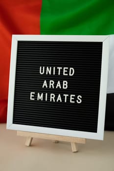 Text UNITED ARAB EMIRATES on background waving flag of UAE. National holiday, Independence Commemoration Day Muslim, congratulations. Arabian holidays. Advertisement of Dubai celebration
