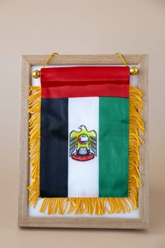 National symbol of UAE. United Arab Emirates small flag with Peregrine falcon on neutral beige background. Copy space for your text. Concept of National day Independence