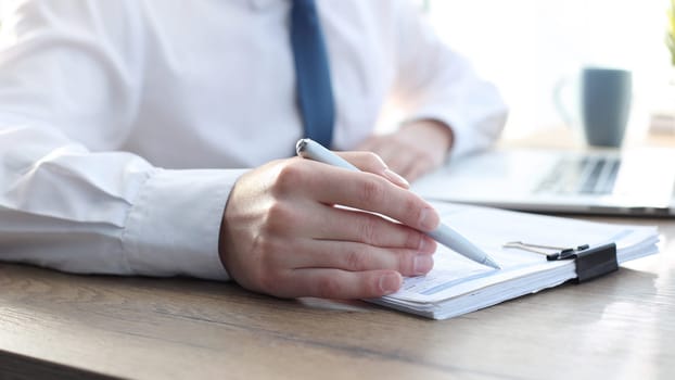 A businessman man in close-up in a shirt checks documents.
