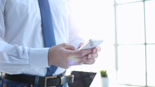 Male businessman in close-up in shirt using phone.