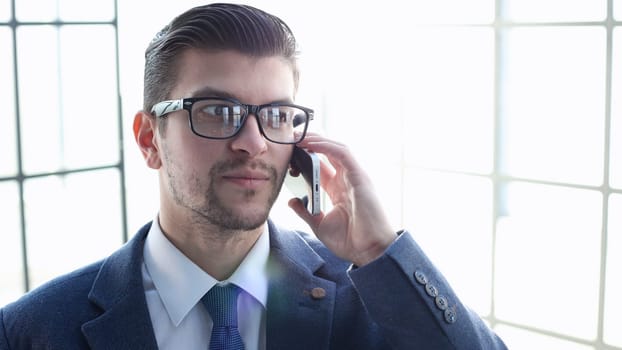 A businessman man in close-up in a shirt talking on the phone.