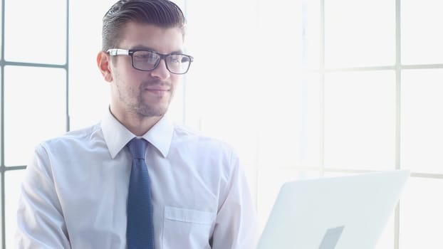 Male businessman in close-up in shirt using laptop.