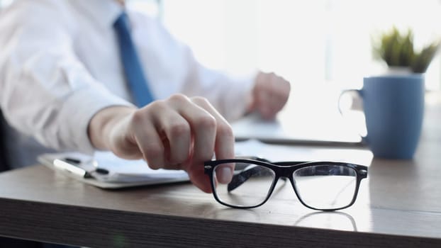 A businessman man in a close-up in a shirt takes glasses.