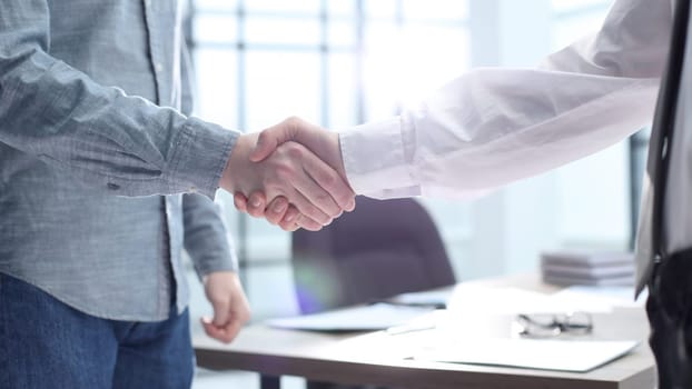 Office workers shake hands in the office.