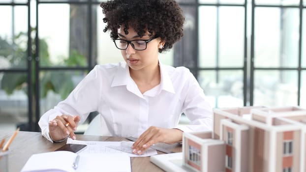 female architect designer examines house layout in office