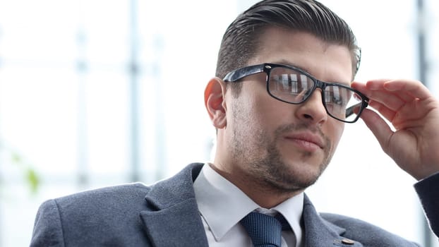 A businessman man with glasses works in an office.