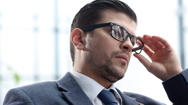 A male businessman works in close-up and adjusts his glasses.