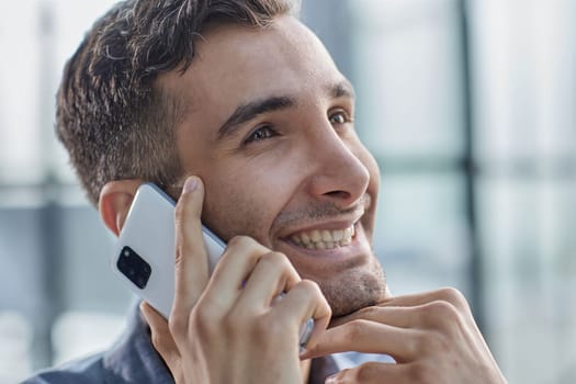 Portrait of young entrepreneur in casual office making phone call while working with laptop