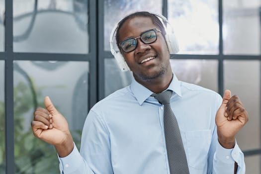 man in a modern office listening to music with white headphones.