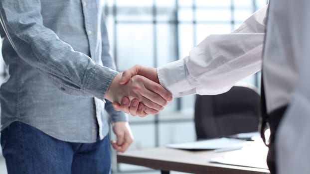Office workers shake hands in the office.