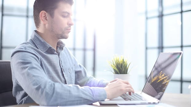 Male office worker in close-up working on a laptop.