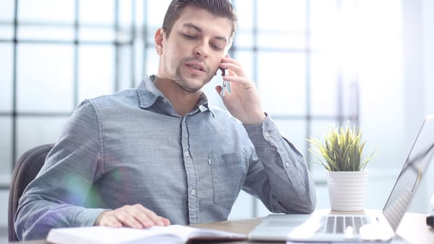 A male office worker is talking on the phone in close-up.