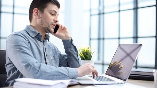 A male office worker is talking on the phone in close-up.