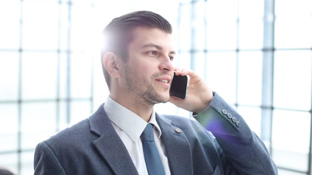A businessman man in close-up in the office talking on the phone.