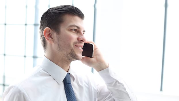 A businessman man in close-up in the office talking on the phone.