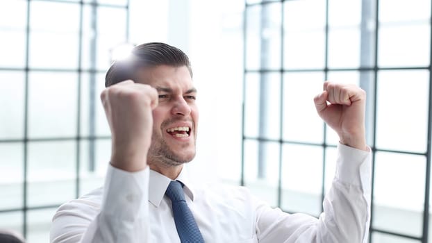 Male businessman in close-up in the office rejoicing.